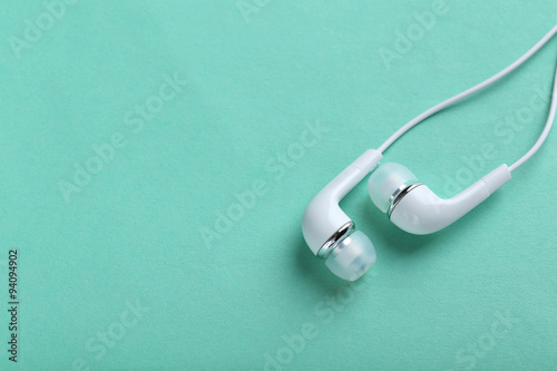 White headphones on a mint paper background