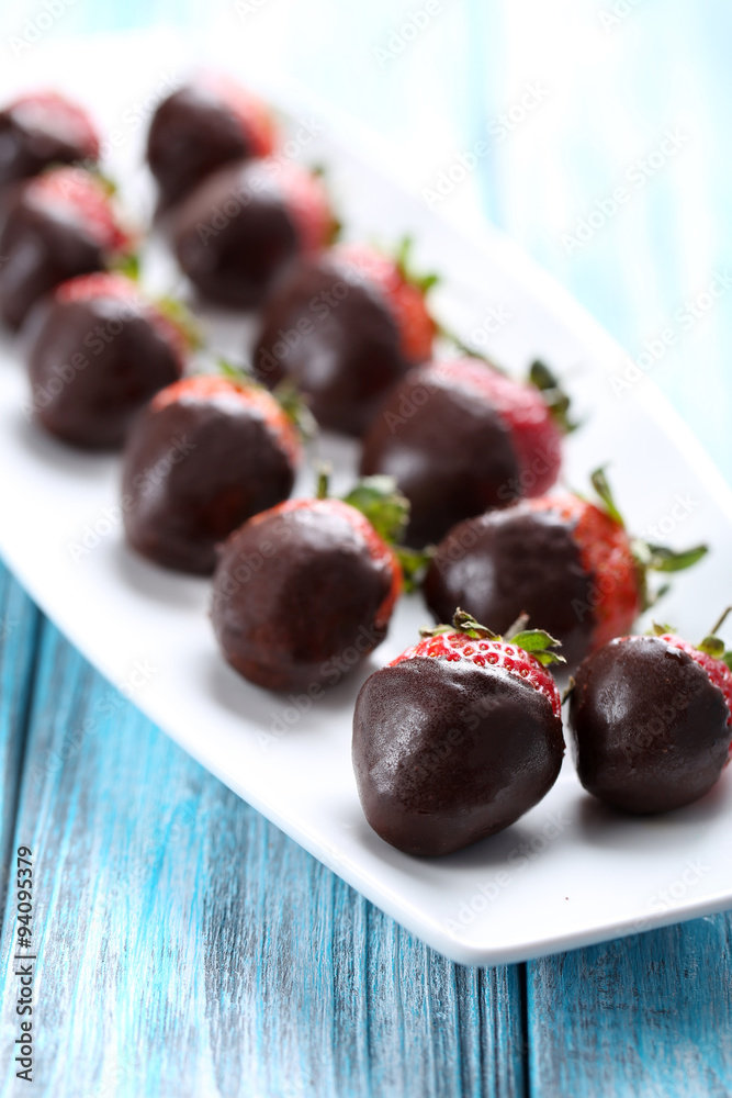 Fresh strawberries dipped in dark chocolate on blue wooden backg Fresh strawberries dipped in dark chocolate on blue wooden backg