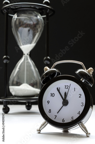 Time passing concept. Black and white with alarm clock and hourglass