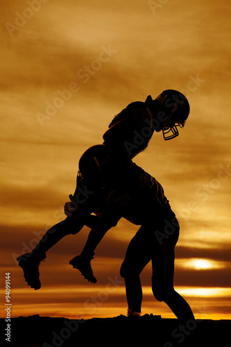 фотографія silhouette of a football player making a hard tackle