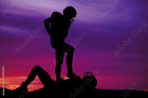 silhouette of a football player with foot on another
