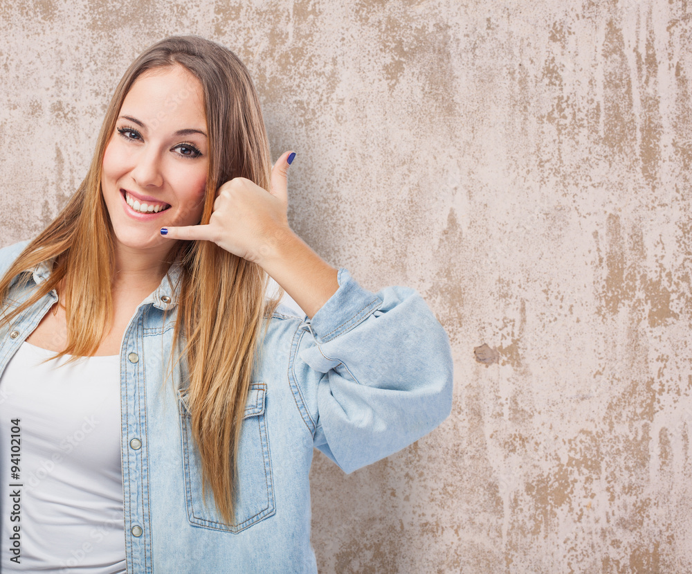 portrait of a pretty young woman making the gesture to call by telephone portrait of a pretty young woman making the gesture to call by telephone