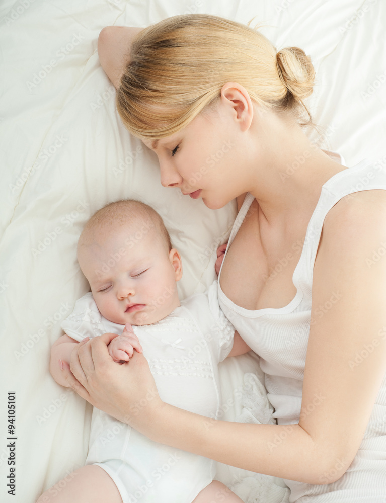 Young mother and her baby, sleeping in bed. Mother and baby. Hap Young mother and her baby, sleeping in bed. Mother and baby. Hap