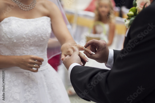 Groom slipping ring on finger of bride at wedding