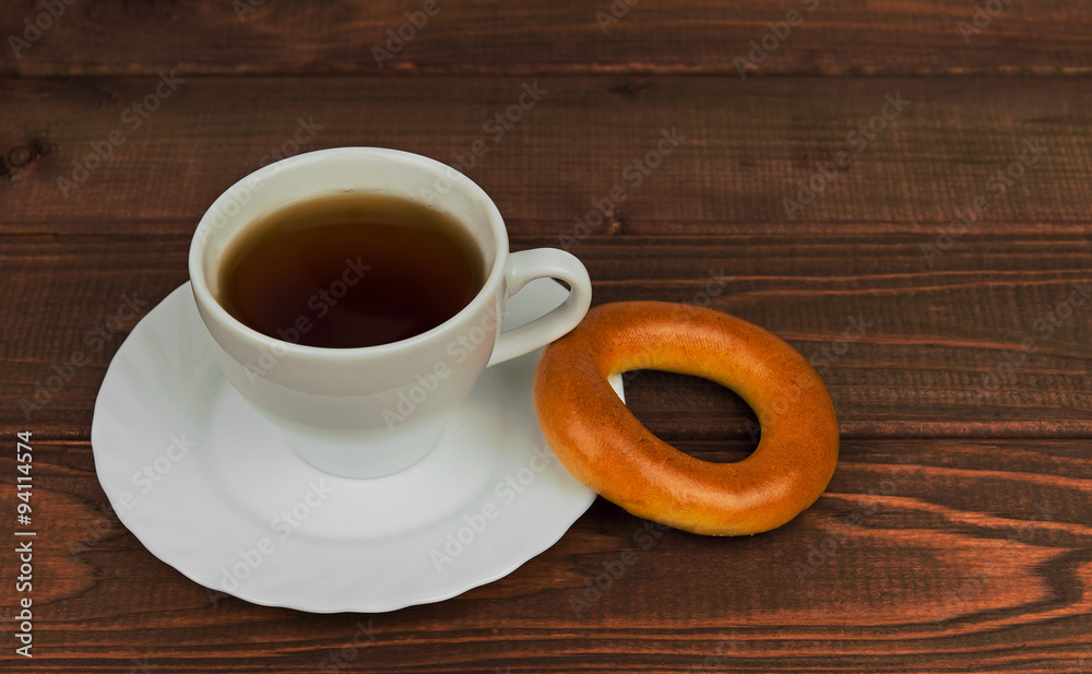 On a wooden table cup of tea and fresh-faced bagel biscuit On a wooden table cup of tea and fresh-faced bagel biscuit
