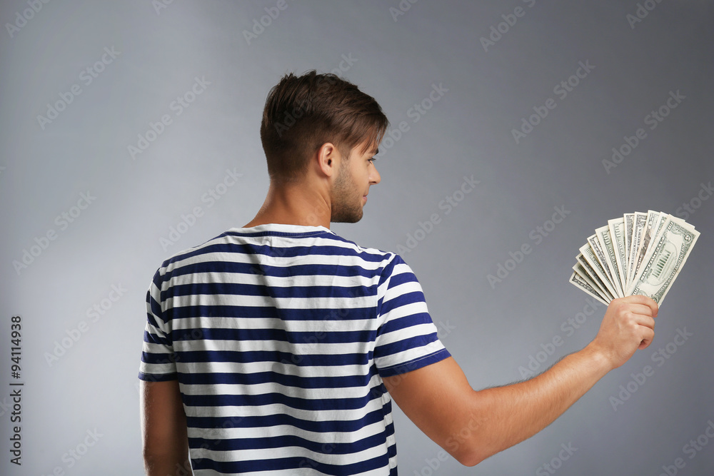 Handsome young man holding money on gray background Handsome young man holding money on gray background