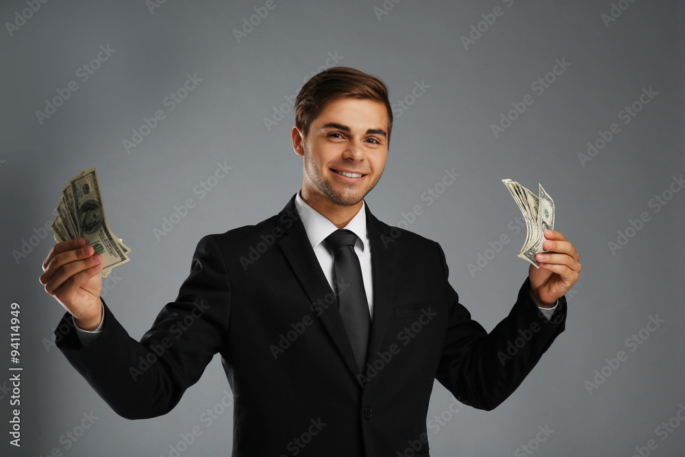 Elegant man in suit holding money on gray background Elegant man in suit holding money on gray background