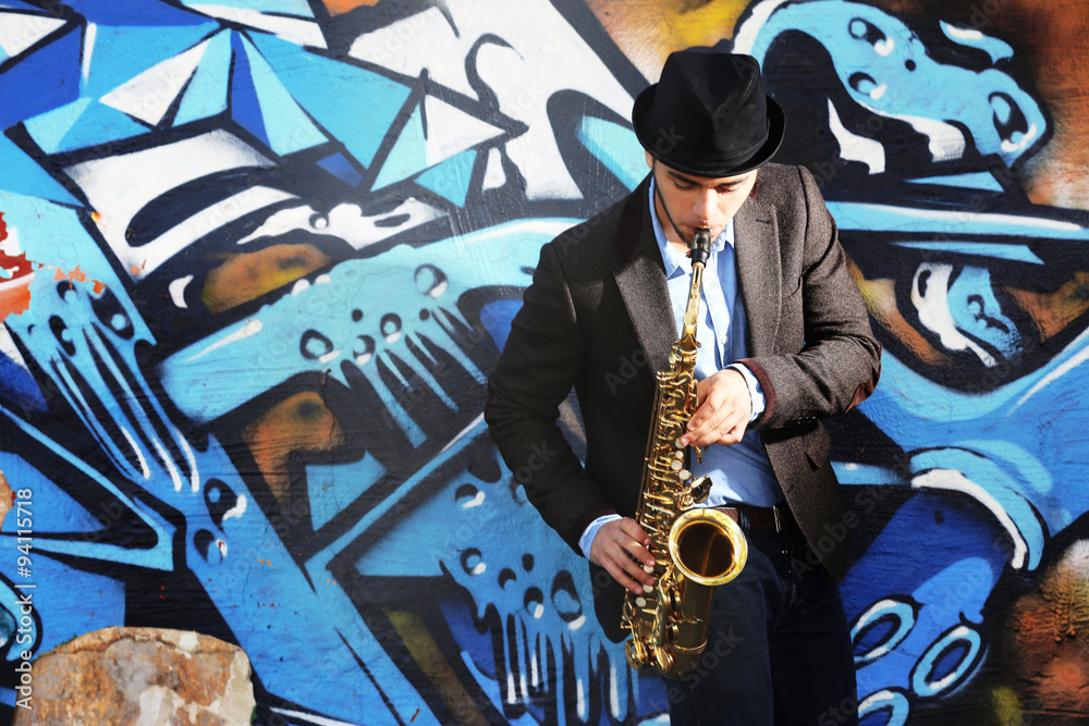 Naklejka premium Saxophone player on graffiti wall background