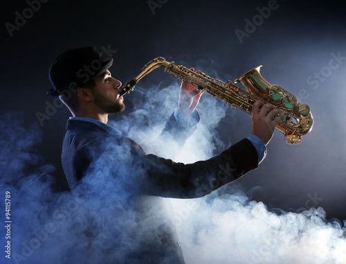 Photography Elegant saxophonist plays jazz on dark background in a smoke