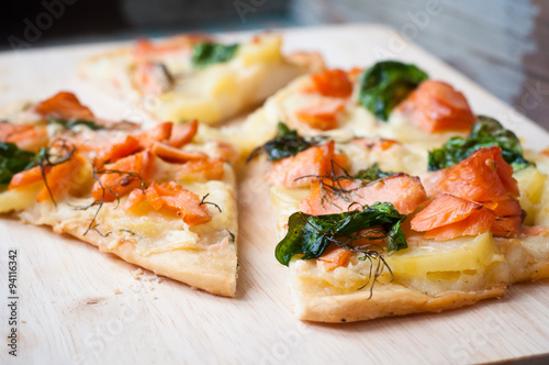 Home made white pizza topped with salmon, cheese and wilted spinach.