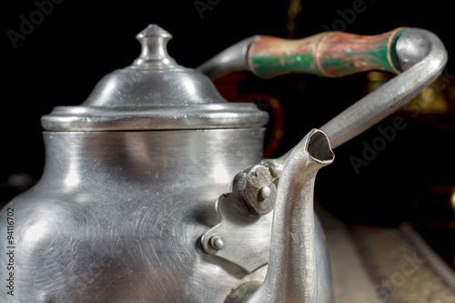 Close-up of ancient metallic teapot with wooden handle