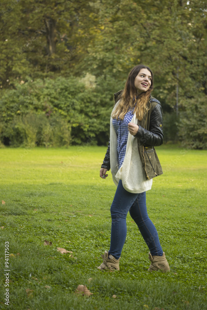 Young beautiful hipster girl walking in park on green grass fiel Young beautiful hipster girl walking in park on green grass fiel