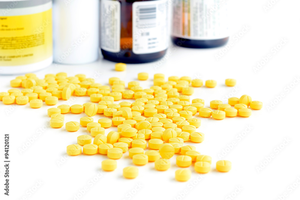 Heap of small yellow tablets (or pills) on white table Heap of small yellow tablets (or pills) on white table