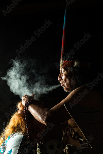 In the heart of the Amazon jungle in Ecuador, a shaman leads a sacred ayahuasca ceremony surrounded by people and mystical smoke. photo