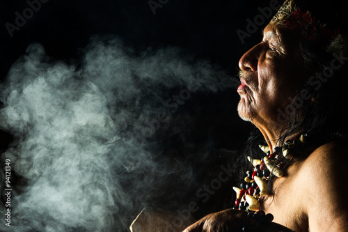 An ancient indigenous tribe in the Amazon, Ecuador, performs a sacred ayahuasca ritual led by a shaman, engulfed in smoke and ancient medicine.