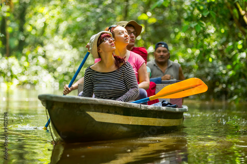 A group of tourists on a boat tour through the lush Amazon rainforest, surrounded by exotic wildlife and dense jungle canopy. photo