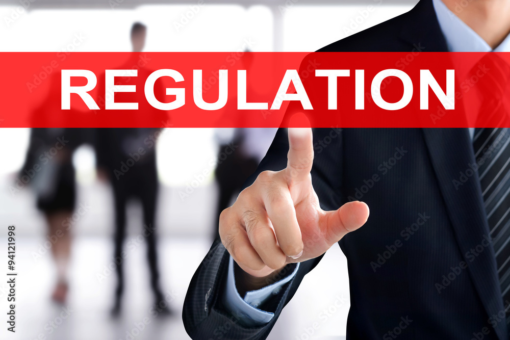 Businessman hand touching REGULATION sign on virtual screen Businessman hand touching REGULATION sign on virtual screen