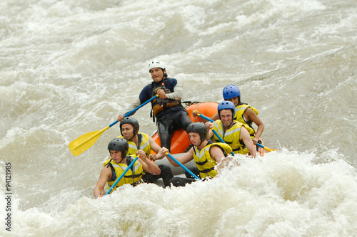 A group of friends navigating the white waters of a river in Ecuador, working together as a team while rafting.