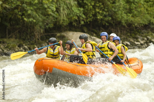 A group of adventurers paddle their white-water raft down a rushing river in Ecuador, enjoying an exciting outdoor team activity and sport.