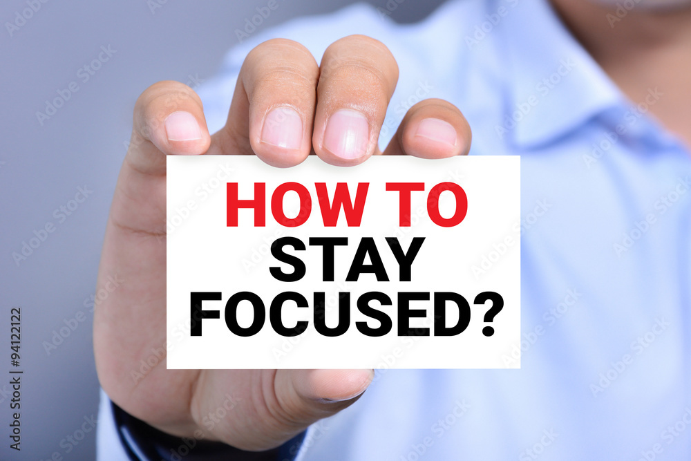HOW TO STAY FOCUSED? message on the card shown by a man HOW TO STAY FOCUSED? message on the card shown by a man