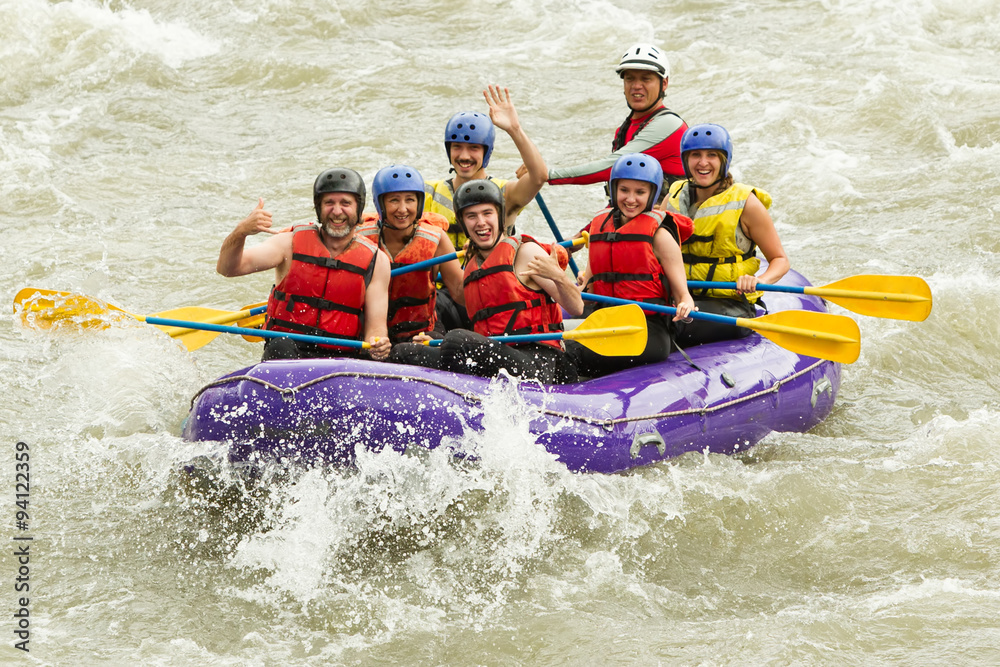 A family of four navigating a white water rafting adventure on a rushing river, their boat bouncing through the extreme rapids.