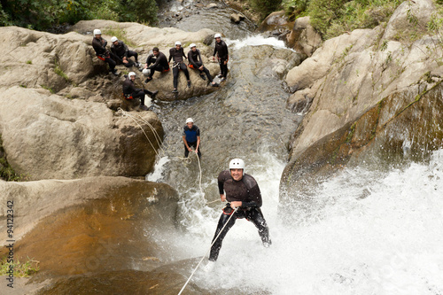 Billede på lærred A man descends a rocky canyon in Ecuador, spelunking through dangerous caves and climbing waterfalls with his extreme sports instructor