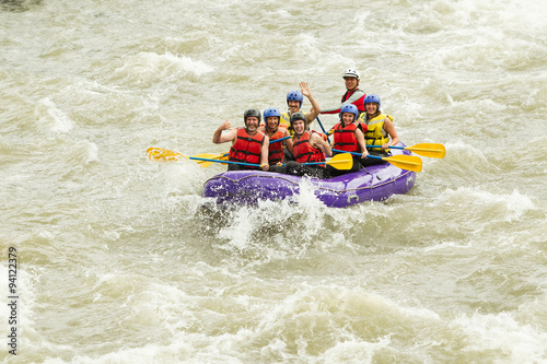 A happy family of seniors enjoying an extreme whitewater rafting adventure on a white water river, working together as a team in their boat.