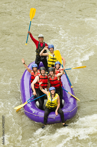 A happy family in a white water rafting team, splashing through the river with excitement and teamwork.