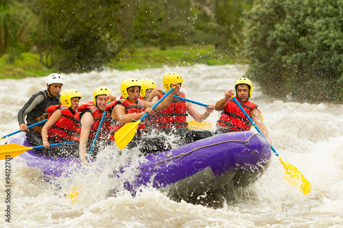 A team of men in Ecuador, surrounded by the wild white waters of a river, showcasing their teamwork and spirit of adventure in rafting competition. © Ammit