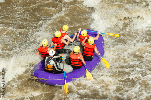 An assembly of daring tourists flanked by a masterful rafting pilot engages the ferocious rapids of an Ecuadorian river encapsulating a blend of adrenaline and scenic vistas