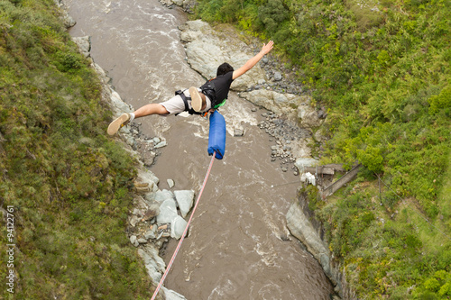 A person bungee jumping off a bridge with a rope, soaring through the air above a stunning waterfall below.
