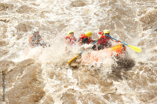 A group of people in a white water rafting team rowing down a river, soaking wet and enjoying the thrill of the adventure.