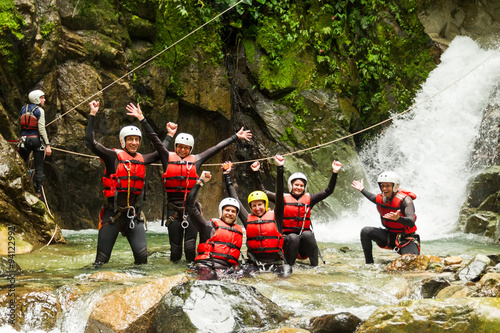 A group of adventurous tourists zip lining through the lush canyons of Ecuador's Llanganates, surrounded by breathtaking scenery and excited people.