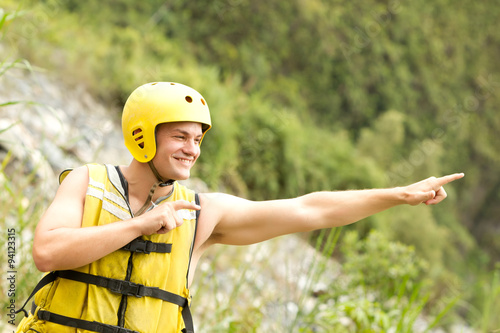 Sporty adult male in standard water sport attire gesturing towards the sky for an exhilarating experience.
