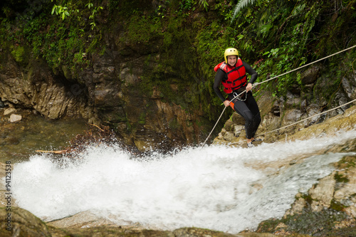 A group of women racing down a waterfall while rappelling during a canyoning descent, each person securely attached to a rope.