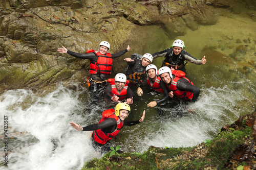 A group of young people in wet canyoning gear, exploring a river in Baños, Ecuador. They are having fun on this adventurous outdoor sport tour. photo