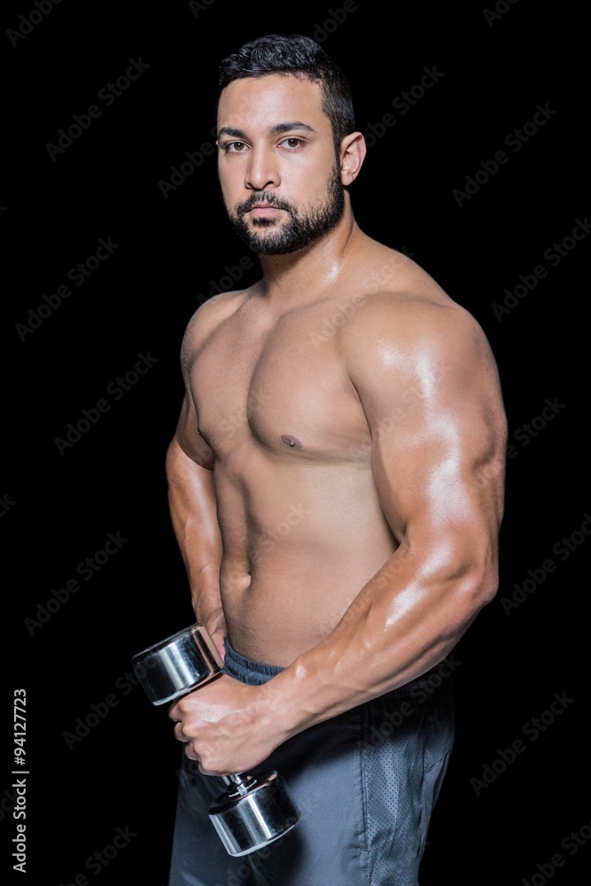 Serious bodybuilder man holding dumbbell