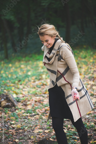 Elegant young woman standing in autumn park outdoor