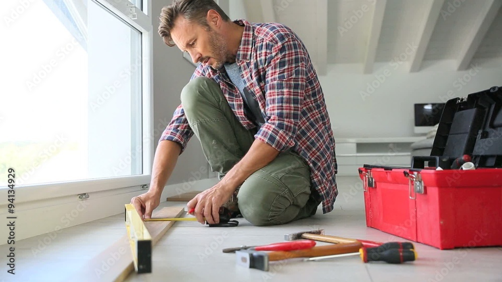 Cheerful man at home installing new wooden floor Cheerful man at home installing new wooden floor