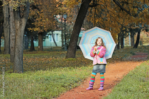 beautiful little girl with umbrella in autumn park