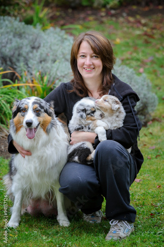 Obraz na plátně Dog breeder with Australian Shepherd adult female dog and her puppies in arms