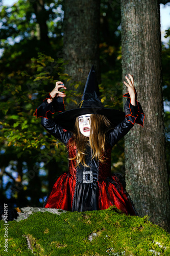 Girl in the forest dressed Halloween witch costume