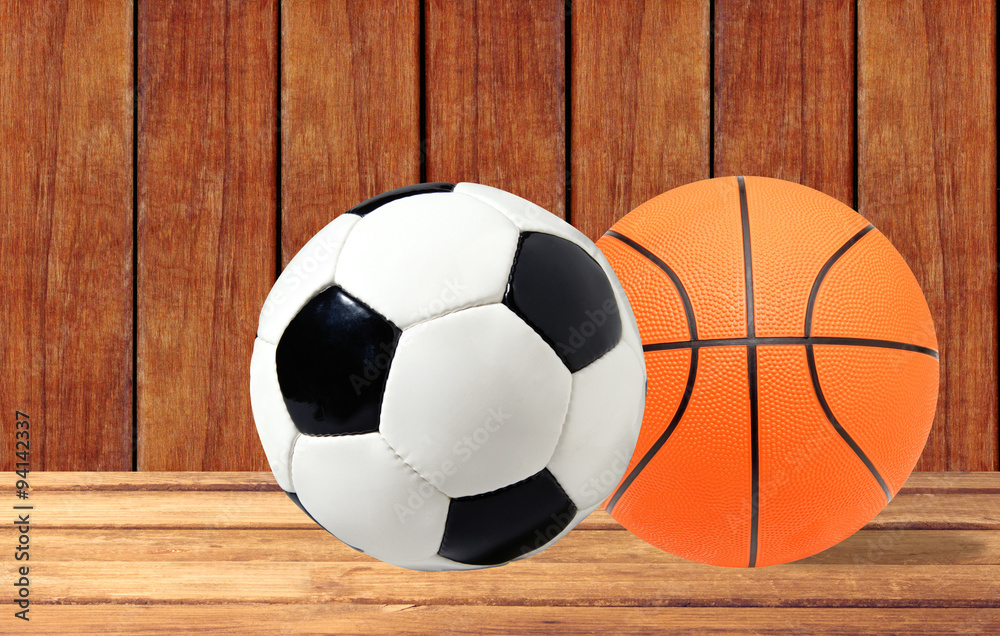 Basketball and soccer ball on the wooden table over wooden backg Basketball and soccer ball on the wooden table over wooden backg
