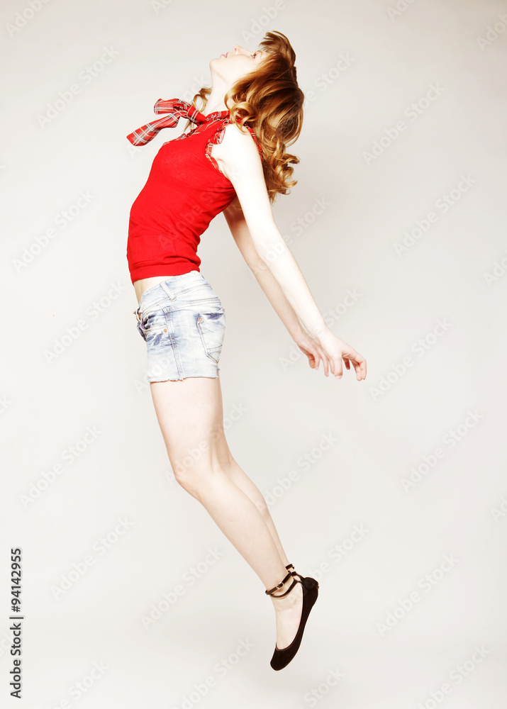 young lady jumping in joy over grey  background