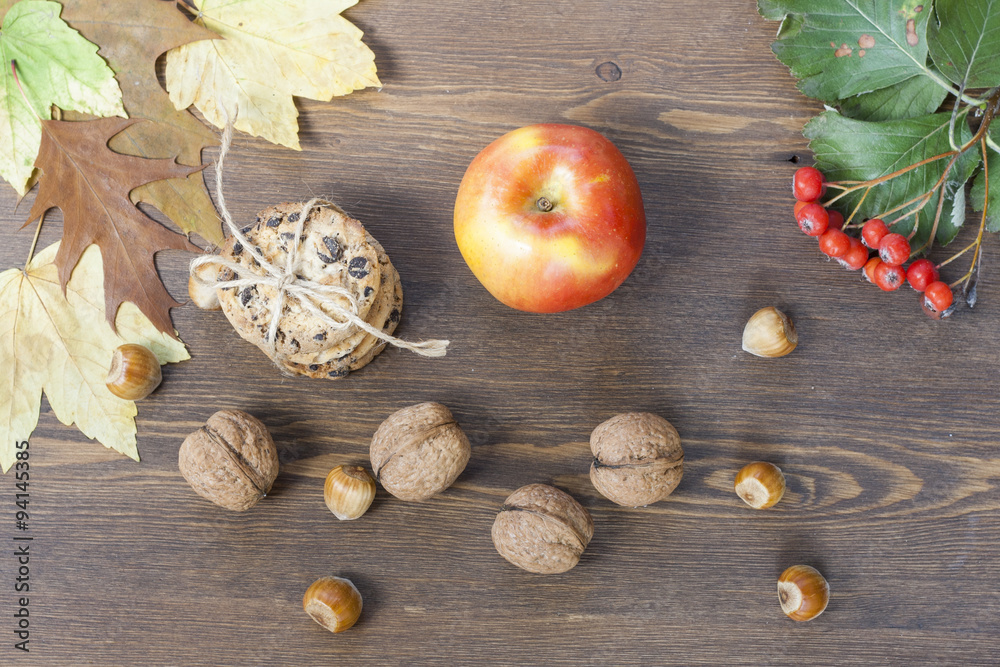 Apple, cookies with chocolate, nuts, mountain ash and red autumn leaves on a wooden table Apple, cookies with chocolate, nuts, mountain ash and red autumn leaves on a wooden table