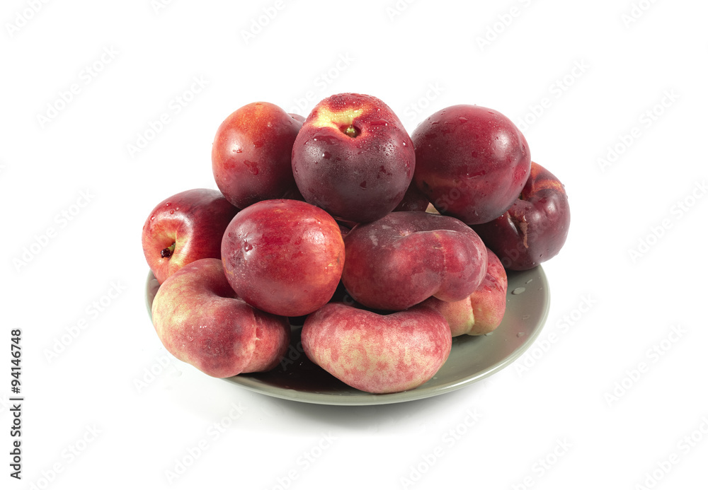 Fresh ripe red peaches with water drops on a ceramic plate isola