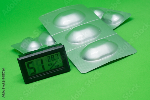 Aluminum of blister pack and digit hygrometer on green backgroun photo