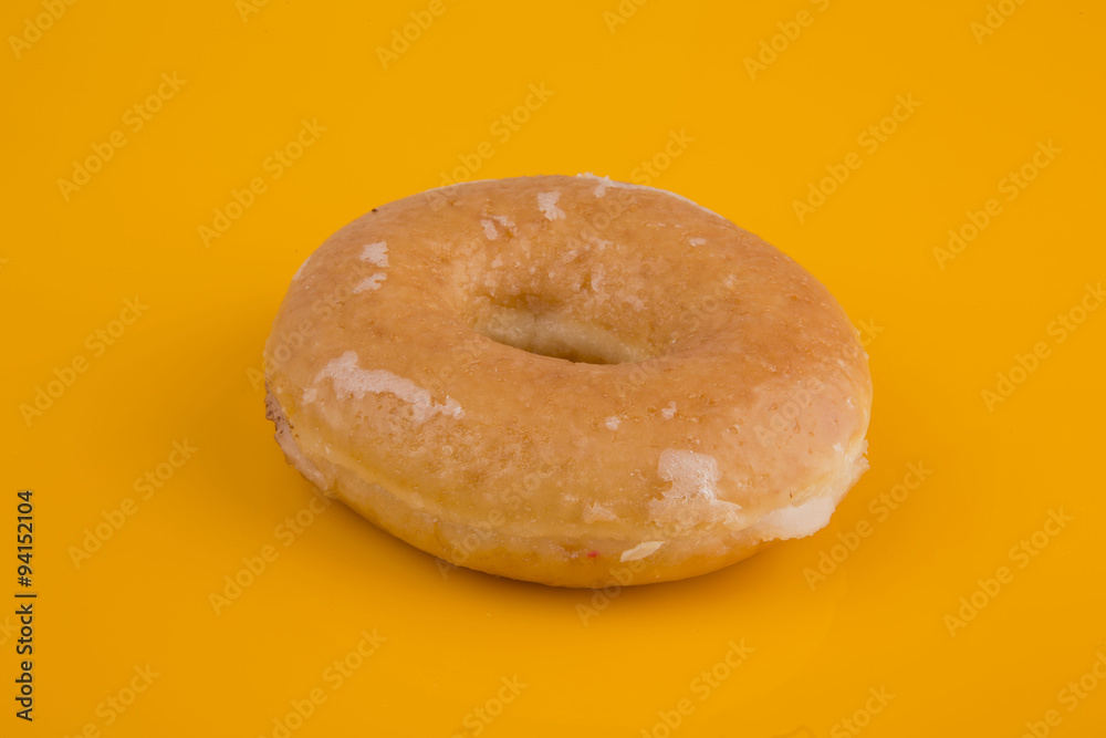 Glazed donut on yellow background Glazed donut on yellow background