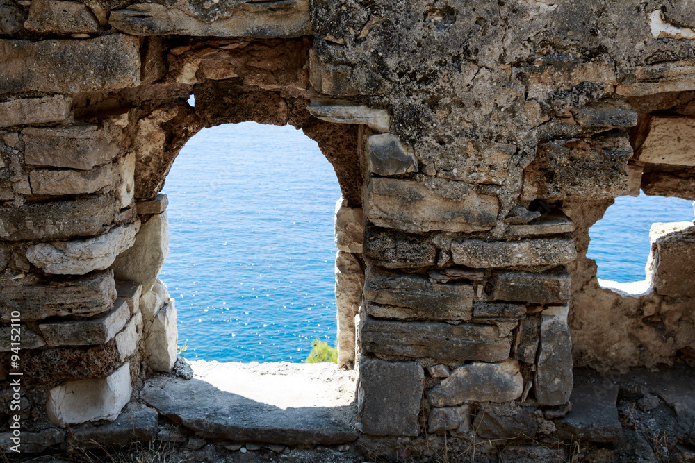 Abandoned ancient ruined wall with windows and view to the sea
