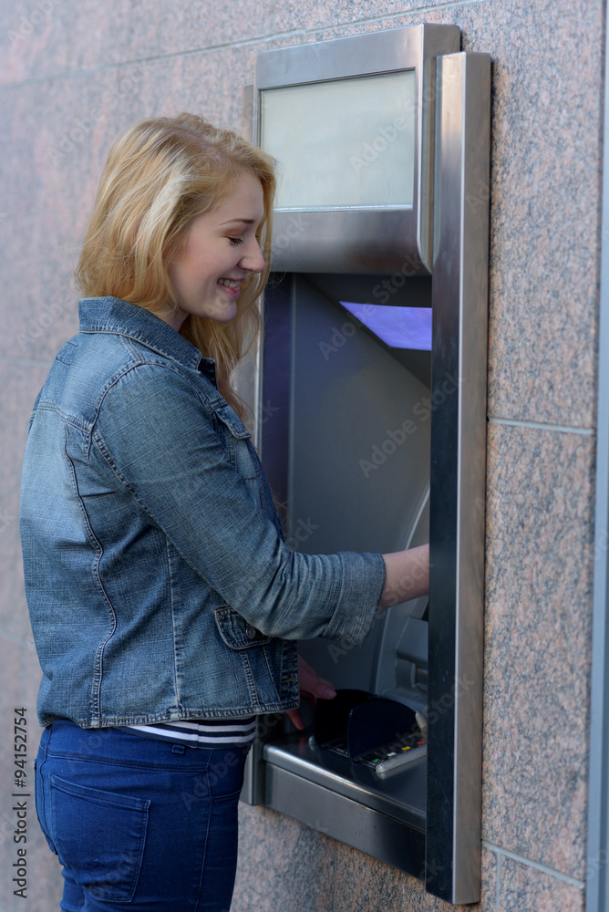 Stylish woman drawing money at an outdoor bank ATM Stylish woman drawing money at an outdoor bank ATM